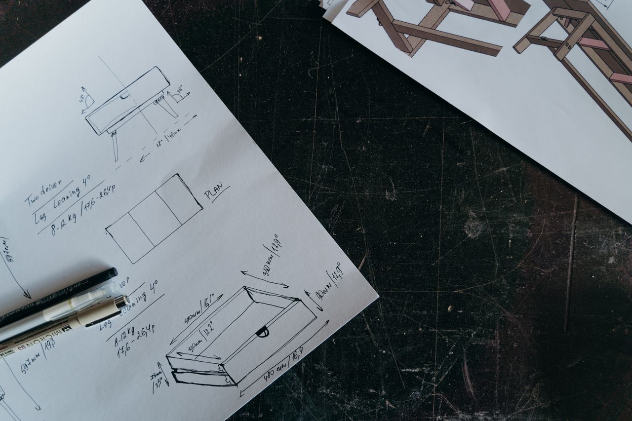 Intricate carpentry design sketches on paper with pens, showcasing furniture project planning.